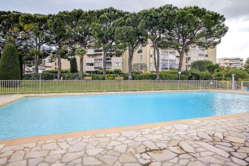une piscine bleue avec une clôture et des arbres dans l'établissement Studio vue mer, piscine - tennis, à Antibes