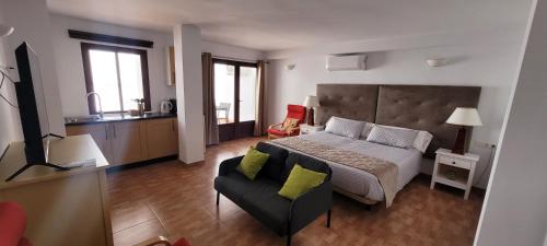 Apartamentos luna في أرداليس: غرفة نوم بسرير واريكة وكرسي