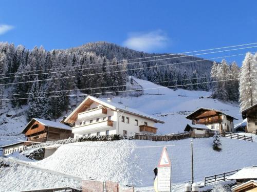 ein Gebäude auf einem verschneiten Hügel mit schneebedeckten Dächern in der Unterkunft Ferienwohnung in schöner Bergkulisse mit zwei Balkonen, sowie einem Spielplatz im Garten in Lappach