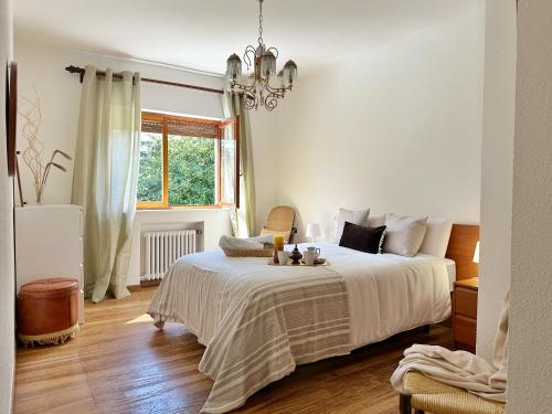 a white bedroom with a bed and a chandelier at Villa La Hojarasca - 6820 in Noja