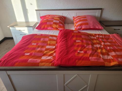 a bed with red and orange blankets and pillows at Am Zimmerkopf in Hermersberg