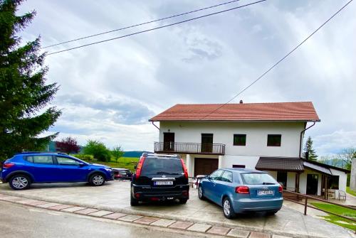 three cars parked in a parking lot in front of a house at Visoravan 1200 in Kupres