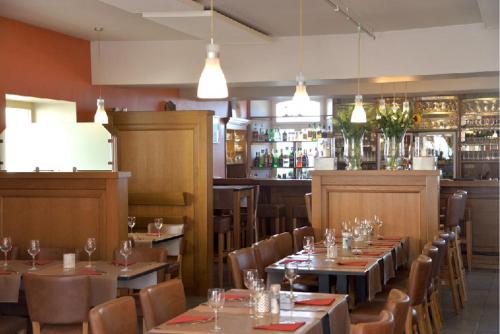 un restaurante con mesas y sillas y un bar en La Couronne en Welkenraedt