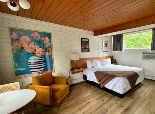 een slaapkamer met een bed en een stoel bij The Sierra Motel in Traverse City