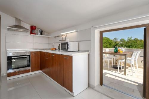 uma cozinha com armários de madeira e uma mesa com uma varanda em Ferienwohnung Residence Mala 1 mit Pool em Funtana