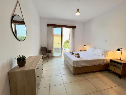een slaapkamer met een bed, een tafel en een spiegel bij Coral Azure in Paphos