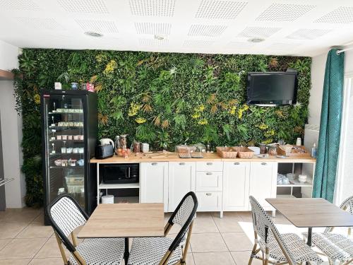 eine Küche mit einer grünen Wand mit Tischen und Stühlen in der Unterkunft Hôtel Ecochic - Mont-de-Marsan in Saint-Pierre-du-Mont