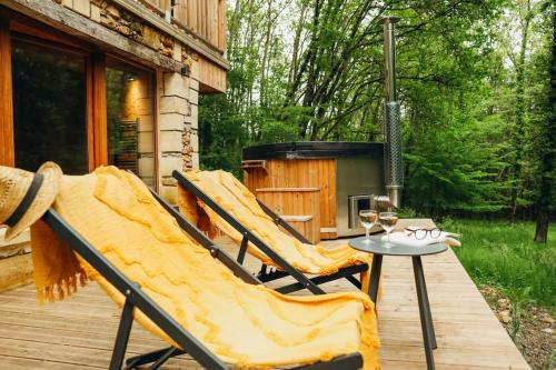 une terrasse avec des chaises et une table avec un bain à remous dans l'établissement La Cachette, espace insolite, à Journiac