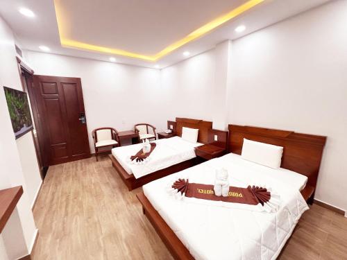 two beds in a room with white walls and wooden floors at Paradise Cu Chi Hotel in Củ Chi