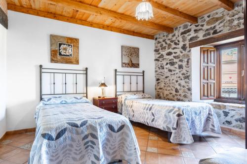 2 Betten in einem Zimmer mit einer Steinmauer in der Unterkunft Casa Transmiera in Solórzano