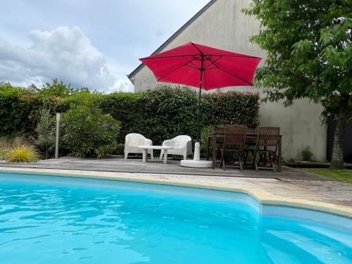 - une table et des chaises avec un parasol rouge à côté de la piscine dans l'établissement Maison familiale Coeur de Loire, à Montlouis-sur-Loire