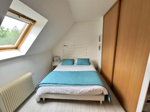 une chambre avec un lit avec des oreillers bleus et une fenêtre dans l'établissement Maison familiale Coeur de Loire, à Montlouis-sur-Loire