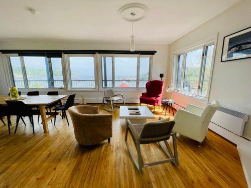 泰道沙克的住宿－La Merveilleuse - Baie de Tadoussac Vue panoramique，客厅配有桌椅和窗户。