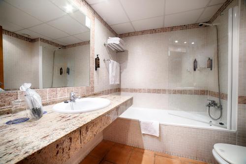 uma casa de banho com um lavatório, uma banheira e um WC. em Ohtels Vil·la Romana em Salou