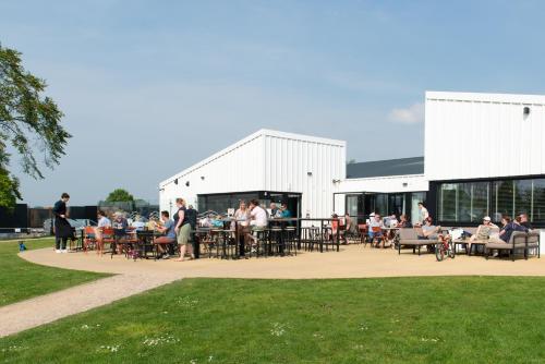 a group of people sitting at tables outside of a building at Kompas Camping Nieuwpoort in Nieuwpoort