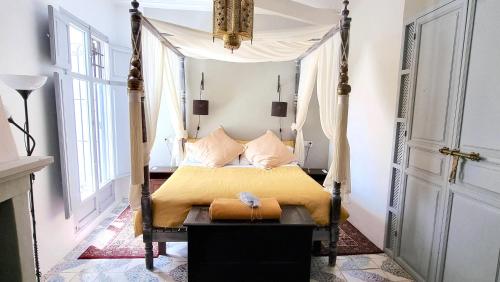 Boutique B&B Número Cuatro في بينيسا: غرفة نوم مع سرير بأربعة أعمدة مع ملاءات صفراء