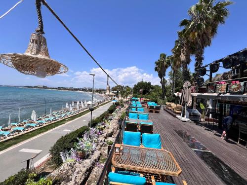 een rij blauwe stoelen op een promenade naast de oceaan bij Cuba Beach Hotel in Side