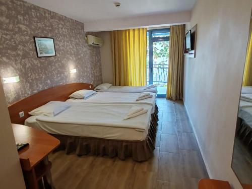 ein Hotelzimmer mit 2 Betten und einem Fenster in der Unterkunft Paloma Hotel in Sonnenstrand
