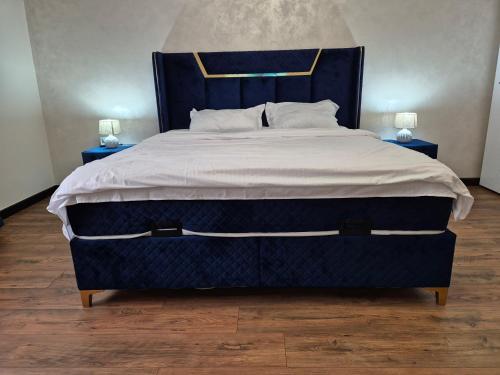 a large bed with a blue headboard and two lamps at Casa Denis la 50m de Castel! in Hunedoara