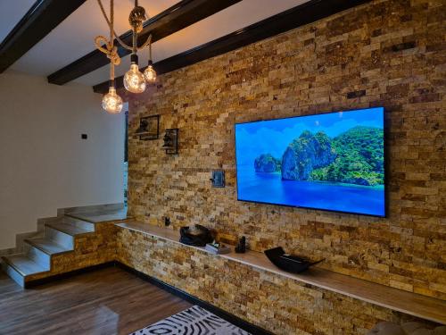a room with a brick wall with a flat screen tv at Casa Denis la 50m de Castel! in Hunedoara