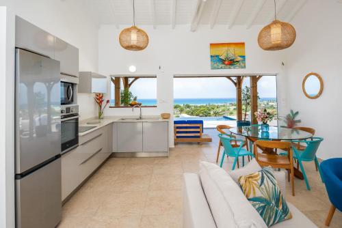 a kitchen and dining room with a view of the ocean at Résidence Les Raisins Clairs - Villas standing 4 étoiles , vue sur mer panoramique & piscine à débordement in Saint-François
