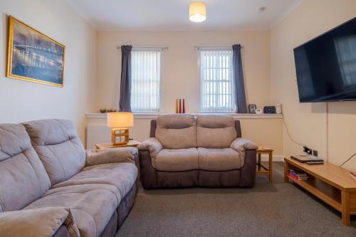 a living room with a couch and a chair and a flat screen tv at Spacious 2-Bedroom Condo With Free Parking On Site in Montrose