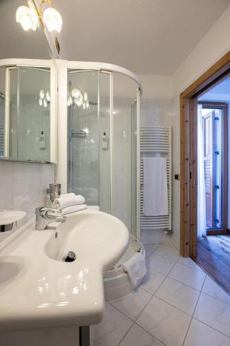 a white bathroom with a sink and a shower at Hotel Stalon Alpine Chic in San Martino di Castrozza
