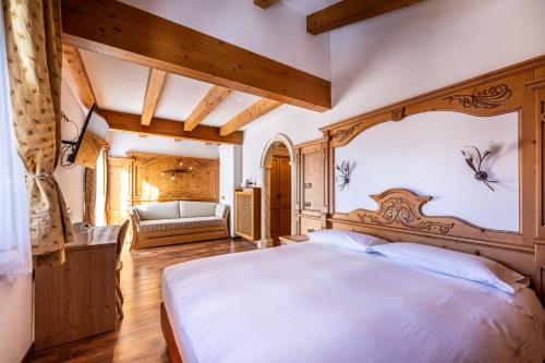a bedroom with a large bed with a wooden headboard at Hotel Stalon Alpine Chic in San Martino di Castrozza