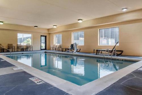 a swimming pool in a hotel with chairs and windows at Comfort Suites Louisville Airport in Louisville