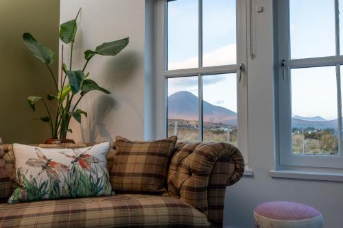 a couch sitting in a living room with windows at Dark Skye Cottage in Broadford