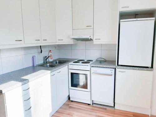 a white kitchen with white cabinets and a sink at Viihtyisä yksiö lähellä Fiskarsin ruukkia in Raasepori