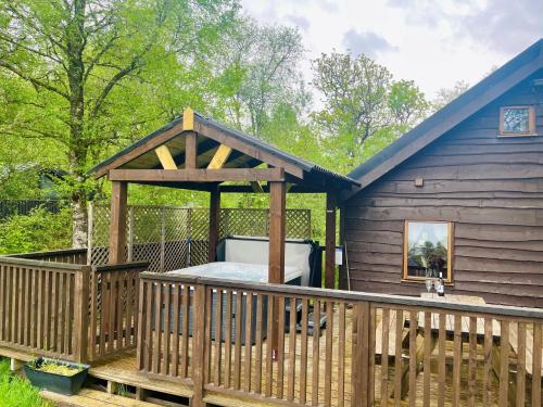 a gazebo with a bed on a deck at Rowan Log Cabin in Dalavich