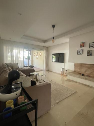 a living room with a couch and a tv at Havre de paix au BahiaGolf Beach, Résidence Front Mer in Bouznika