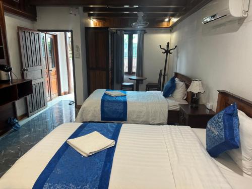 a bedroom with two beds with blue and white sheets at NamKhan Riverside in Luang Prabang