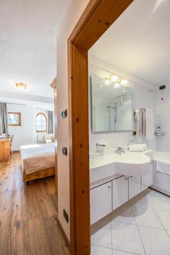 a bathroom with two sinks and a bed in a room at Hotel Stalon Alpine Chic in San Martino di Castrozza