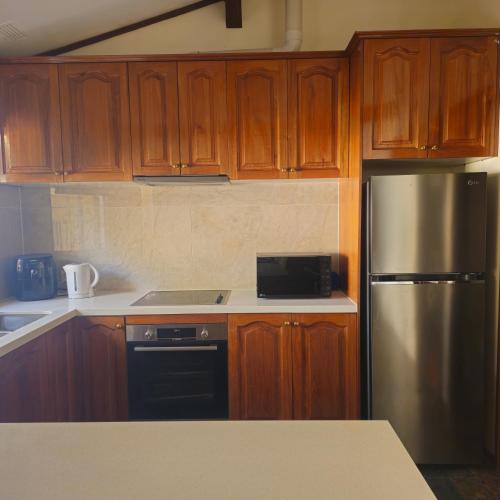 a kitchen with wooden cabinets and a stainless steel refrigerator at Entire 3 bedroom personal house in Chipping Norton in Chipping Norton