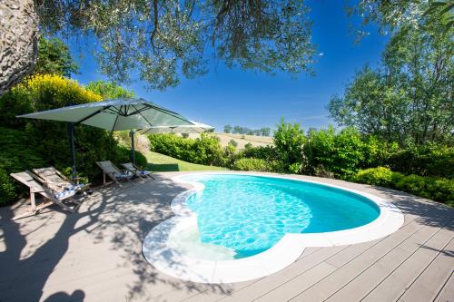 a swimming pool with an umbrella and a table and chairs at Casali Marchigiani - Ville vacanza private con piscina in Ostra