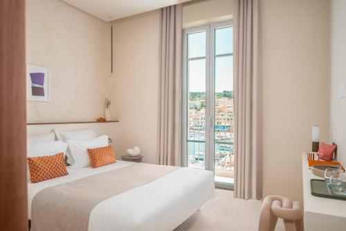 a bedroom with a large bed and a large window at Hotel Liautaud in Cassis