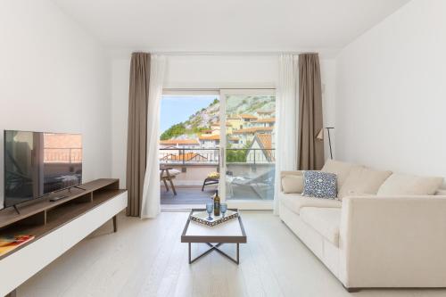 a living room with a white couch and a tv at Portopiccolo Apartments in Sistiana
