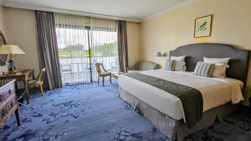 um quarto de hotel com uma cama grande e uma varanda em Relais de Margaux - Hôtel & Spa em Margaux