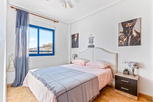 a white bedroom with a bed and a window at Apartamento Mandarín Playamarina 2 in Orihuela