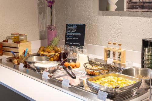 a buffet with bowls of food on a counter at Kyriad Auxerre Appoigny in Appoigny