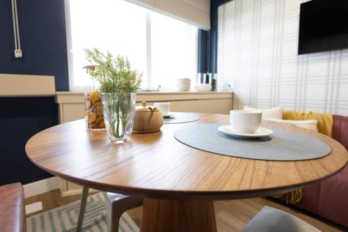 a wooden table with two cups and a vase on it at Suíte LUXO com amenities | Hotel renomado- Paraíso in Sao Paulo