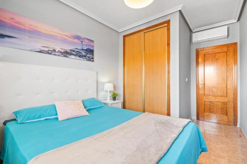 Un dormitorio con una cama azul y una puerta de madera. en Apartamento Lavanda, en Orihuela