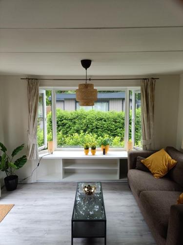 uma sala de estar com um sofá e uma janela em Huisje Veluwe bij Putten aan het Speuldersbos em Putten