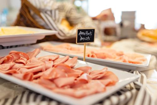 Hotel Mauritius Sentirsi come a Casa في ريتشيوني: طاولة عليها أطباق من اللحوم معروضة مع لافتة