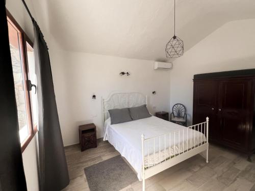 ein Schlafzimmer mit einem weißen Bett in einem Zimmer in der Unterkunft Vivelorural Abuela María 1, chill garden pool in San Bartolomé de Tirajana