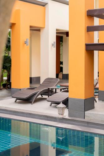 a pool with lounge chairs next to a building at Luxury Thai Style Swimming Pool Villa, Private housekeeper,6 Bedrooms in Nong Prue