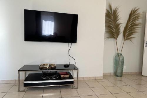 un salon avec une table et une télévision au mur dans l'établissement Apartment in Croix des Gardes, à Cannes