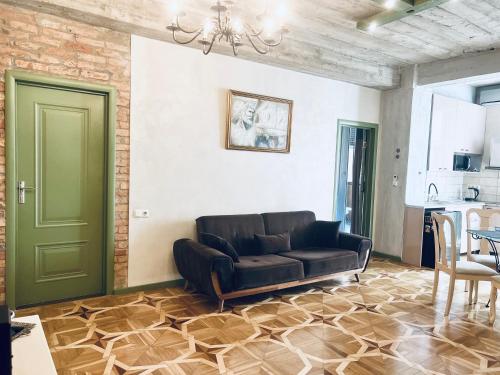 a living room with a black couch and a green door at T2&T3 Apartments LEVANTO in Tbilisi City